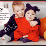 Baby's First Halloween: a baby in a pumpkin costume sitting next to a toddler in a black costume, surrounded by festive Halloween decorations